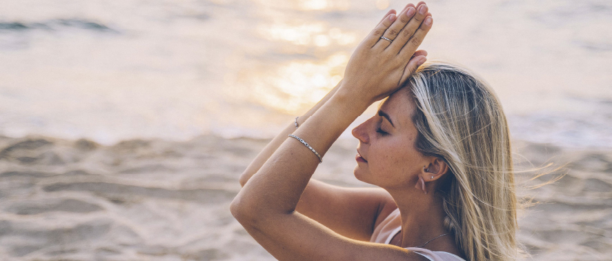 Mujer meditando en la playa al atardecer